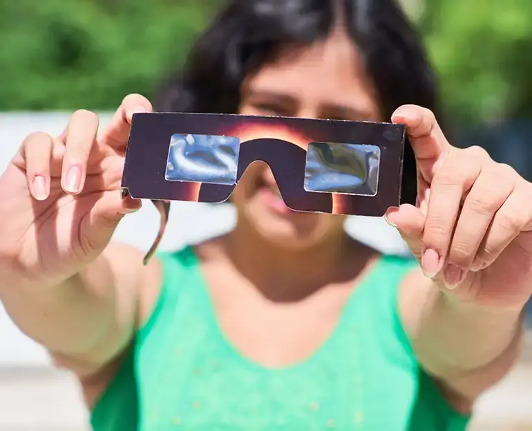 Person holding solar eclipse glasses up for inspection