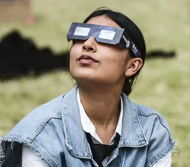Woman observing the sky with certified solar eclipse glasses