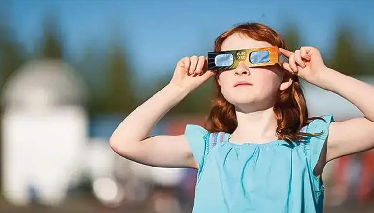 Child safely watching the sun using solar eclipse glasses