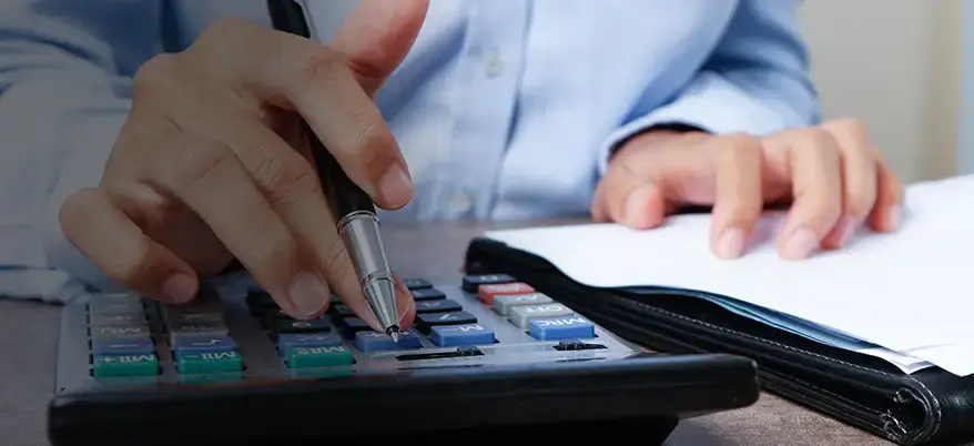 Business person calculating costs with calculator and documents for Spectrum Eclipse Glasses wholesale orders.