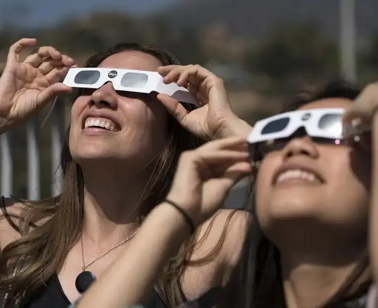 Women safely watching a solar eclipse using ISO-certified Spectrum Eclipse Glasses