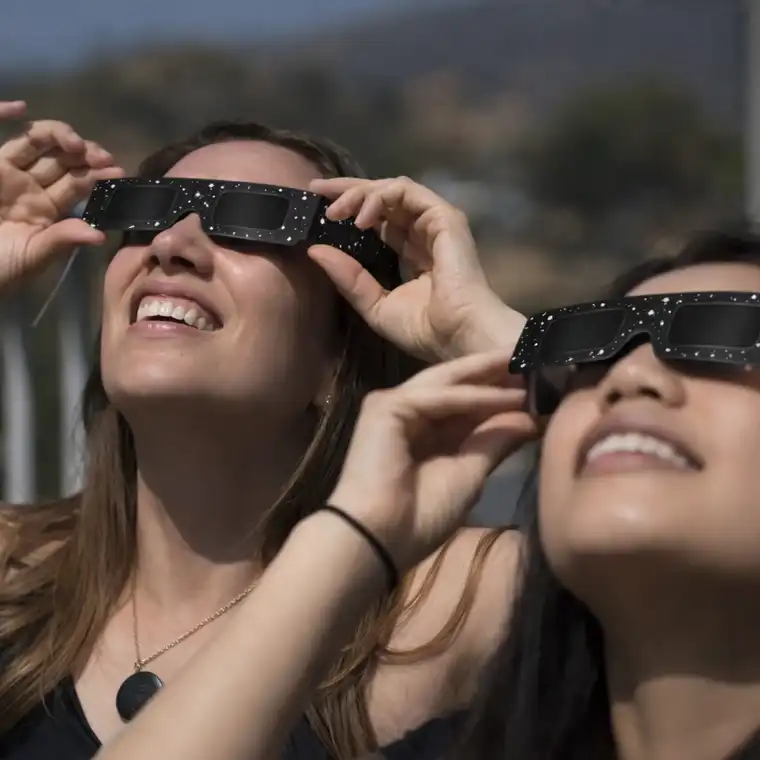 Women safely watching a solar eclipse using ISO-certified Spectrum Eclipse Glasses